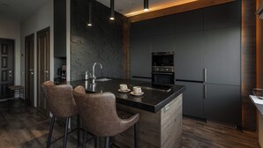 Una cocina moderna con una isla central, taburetes de bar y electrodomésticos integrados.