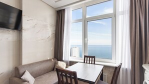 Una habitación con sofá, una mesa y ventana con vista al mar.
