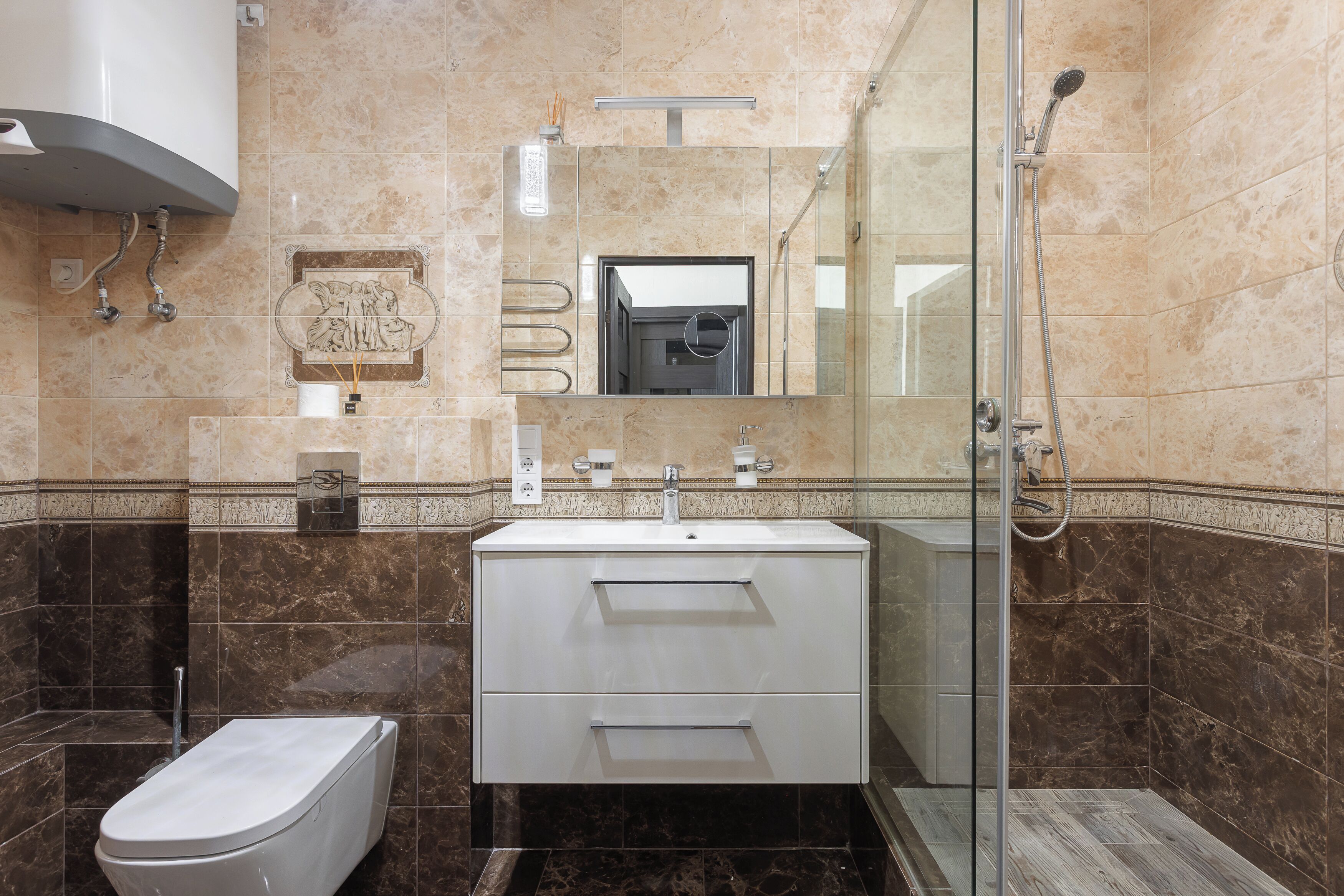 A modern bathroom with a glass-enclosed shower, a white sink, and a marble-tiled wall.