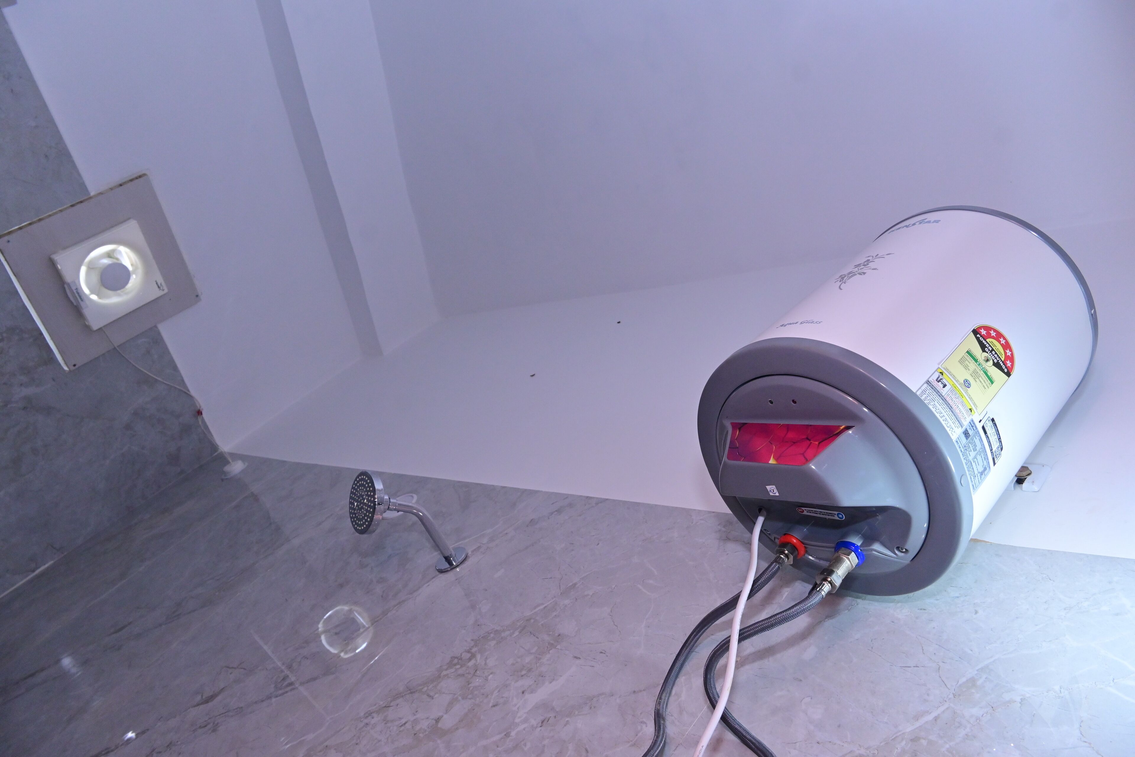A water heater mounted on a wall with a visible control panel and a flexible hose connected to it.