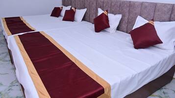 A double bed with a white and maroon bedspread, multiple pillows, and a headboard.