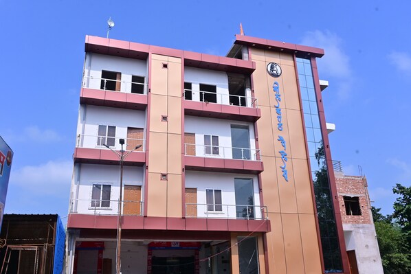 A multi-story building with a prominent clock tower, a sign with foreign script, and a visible ATM on the ground floor. - HOTEL NEELKANTH PALACE (Misrikh)