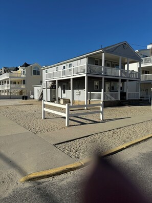 A beachfront building with multiple balconies and a covered porch area.