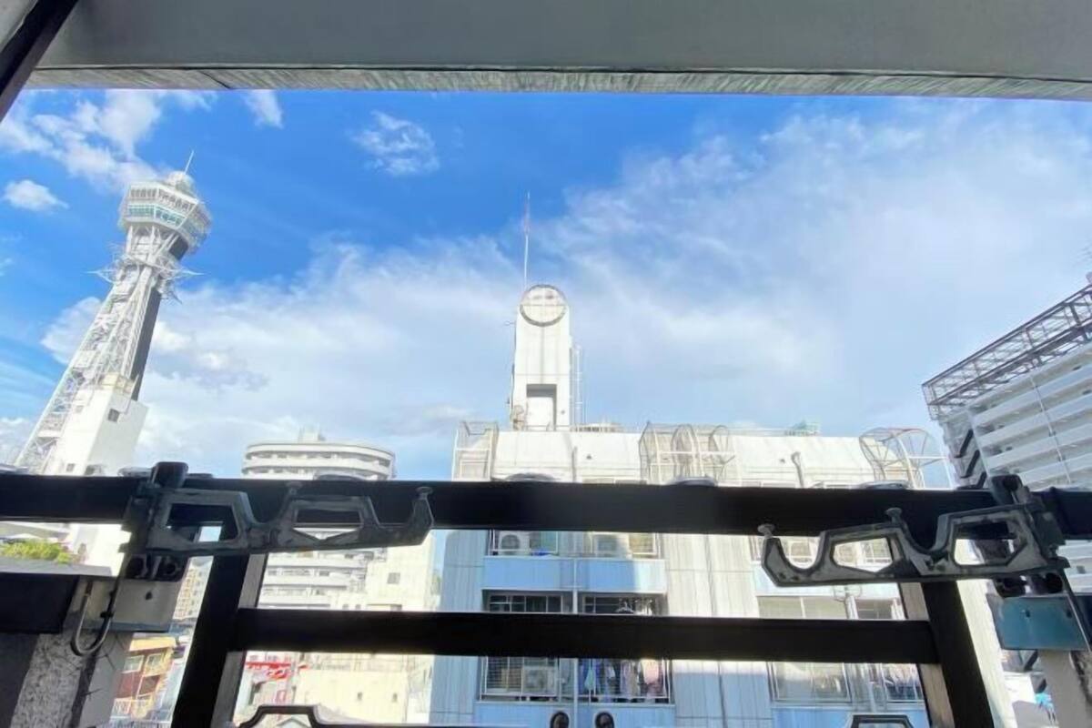 Vista de una torre alta y un campanario a través de una ventana, con edificios al fondo.