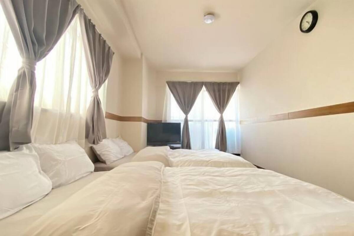 Una habitación de hotel con dos camas, televisión y cortinas.