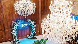 A banquet hall with a large chandelier, floral arch, and tables set for a formal event. - P.A. Smith Hotel (Navasota)