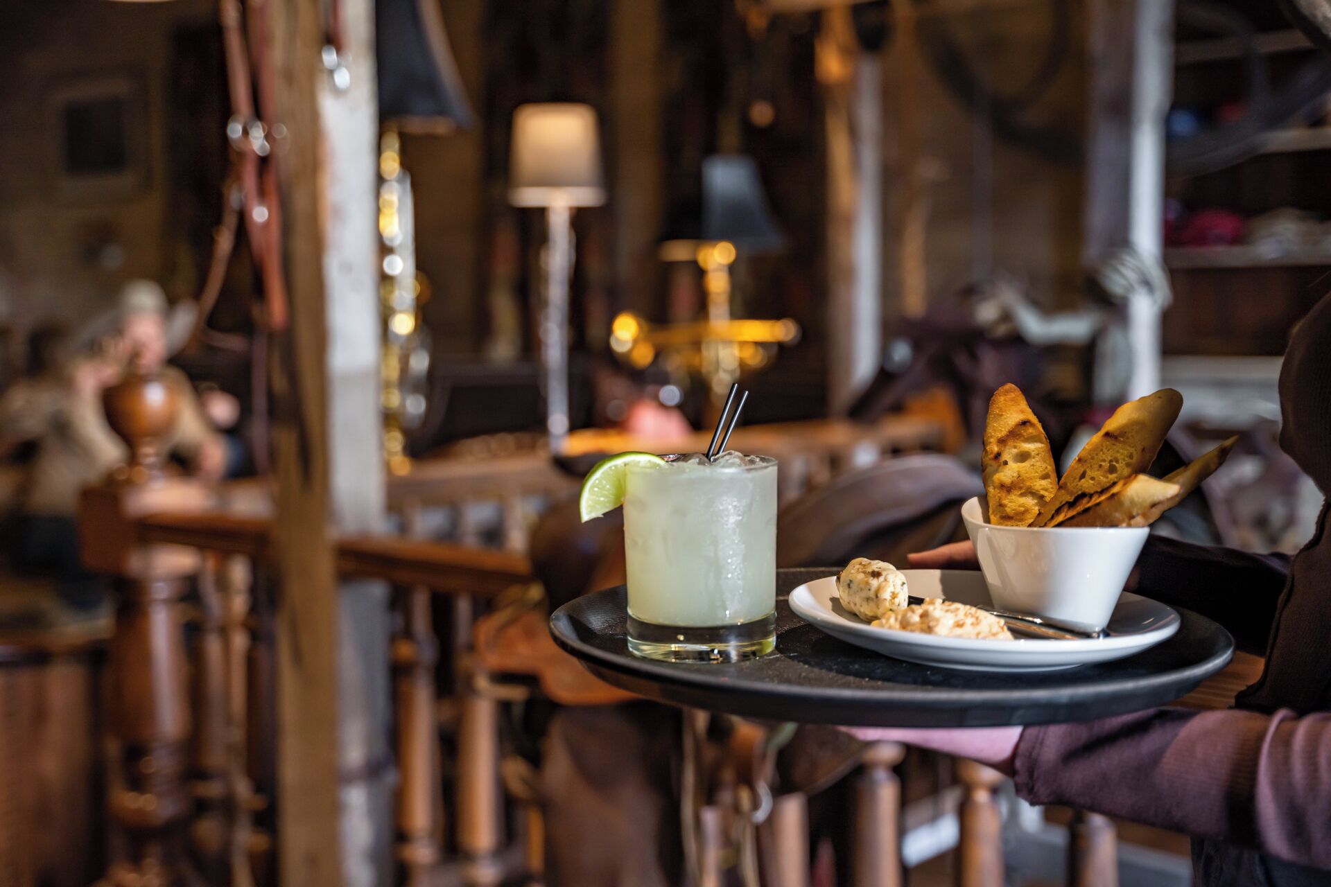 A tray with a drink, bread, and a small plate of food in a restaurant setting.