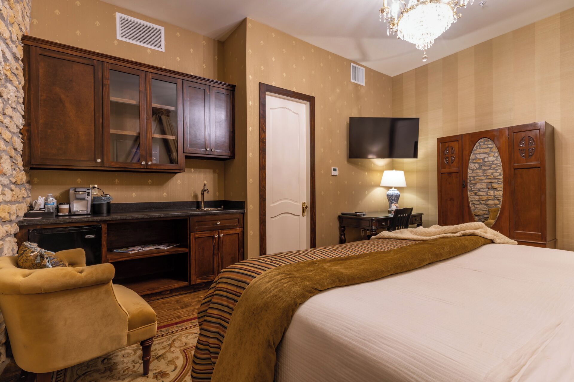 A hotel room with a bed, a desk with a computer, a TV, and a wardrobe.