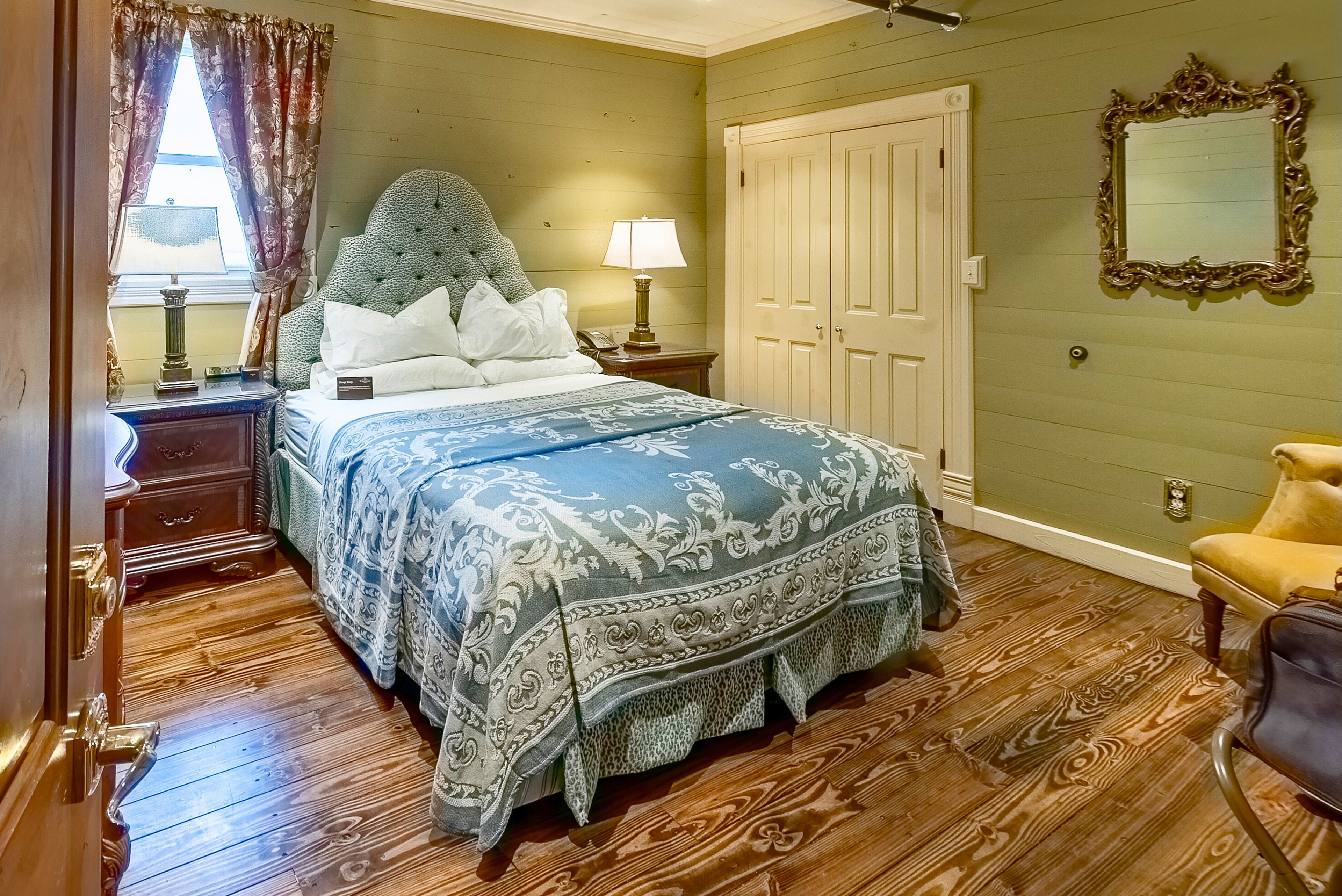 A bedroom with a bed, nightstand, lamp, dresser, and a door.