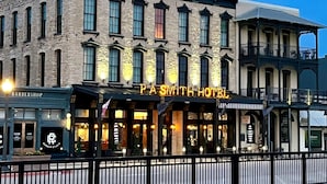 The exterior of the PASSMITH HOTEL with a stone facade, large windows, and a balcony area. - P.A. Smith Hotel (Navasota)