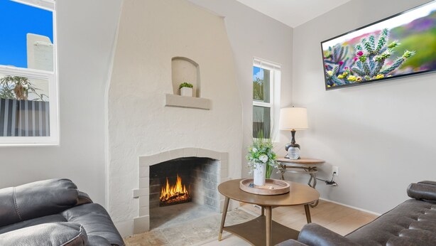 Ein Wohnzimmer mit Kamin, einer Couch, einem Couchtisch und einem an der Wand montierten Fernseher.