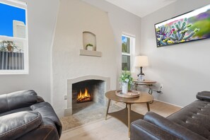 Un salon avec une cheminée, un canapé, une table basse et un téléviseur fixé au mur.