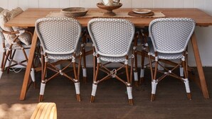 A dining area with a wooden table, wicker chairs, and a fish-themed wall hanging.