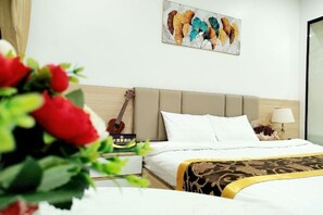 A hotel room with a bed, a guitar, a painting, and a lamp.