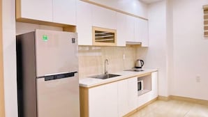 Una cocina moderna con armarios blancos, un refrigerador de acero inoxidable, un fregadero y una cafetera.