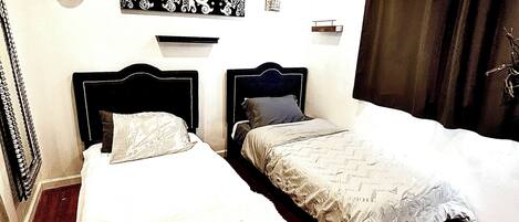 A bedroom with two beds, a ceiling fan, and a window with curtains.