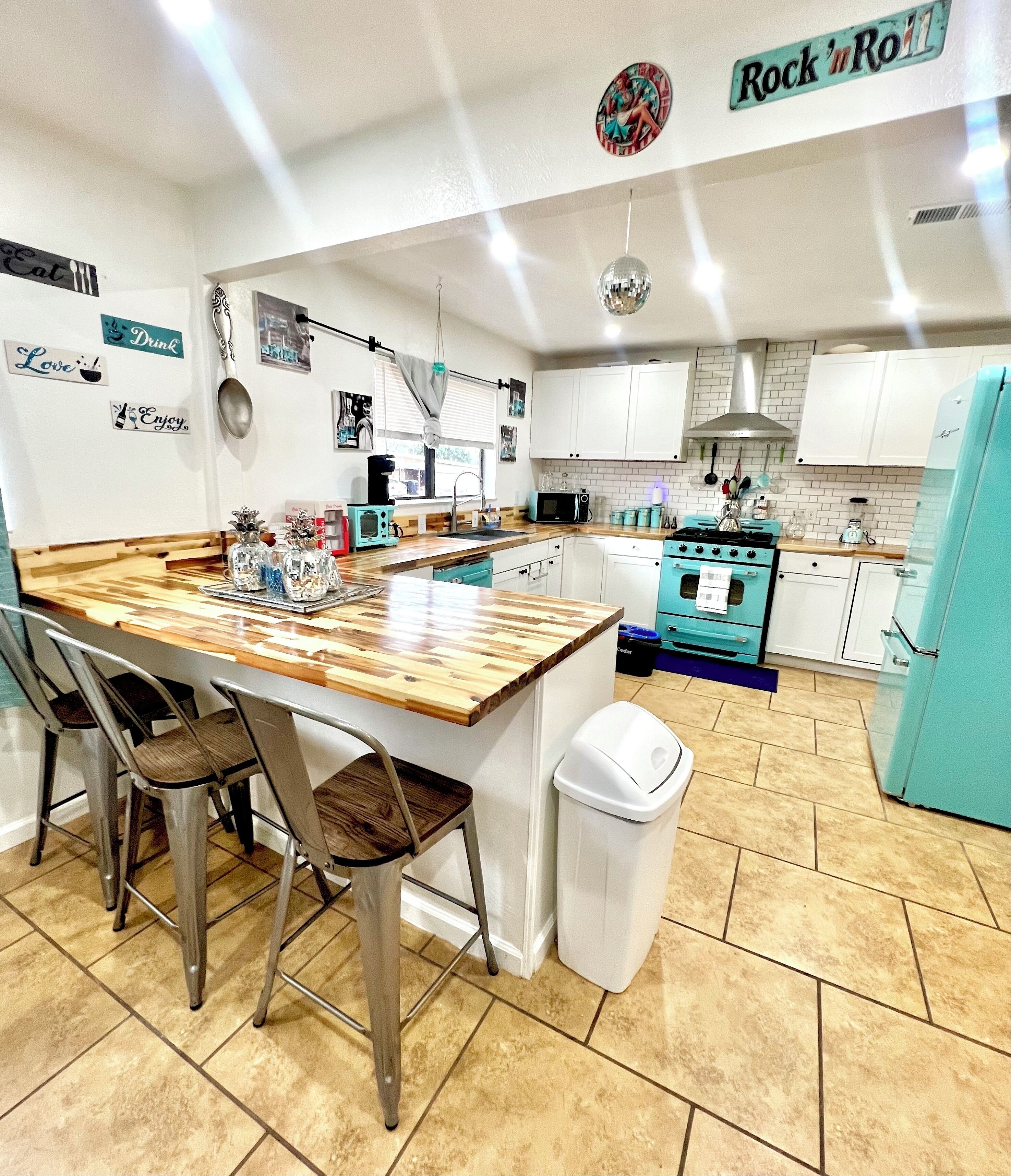 A kitchen with a central island, white cabinets, a blue stove, and a white trash bin.