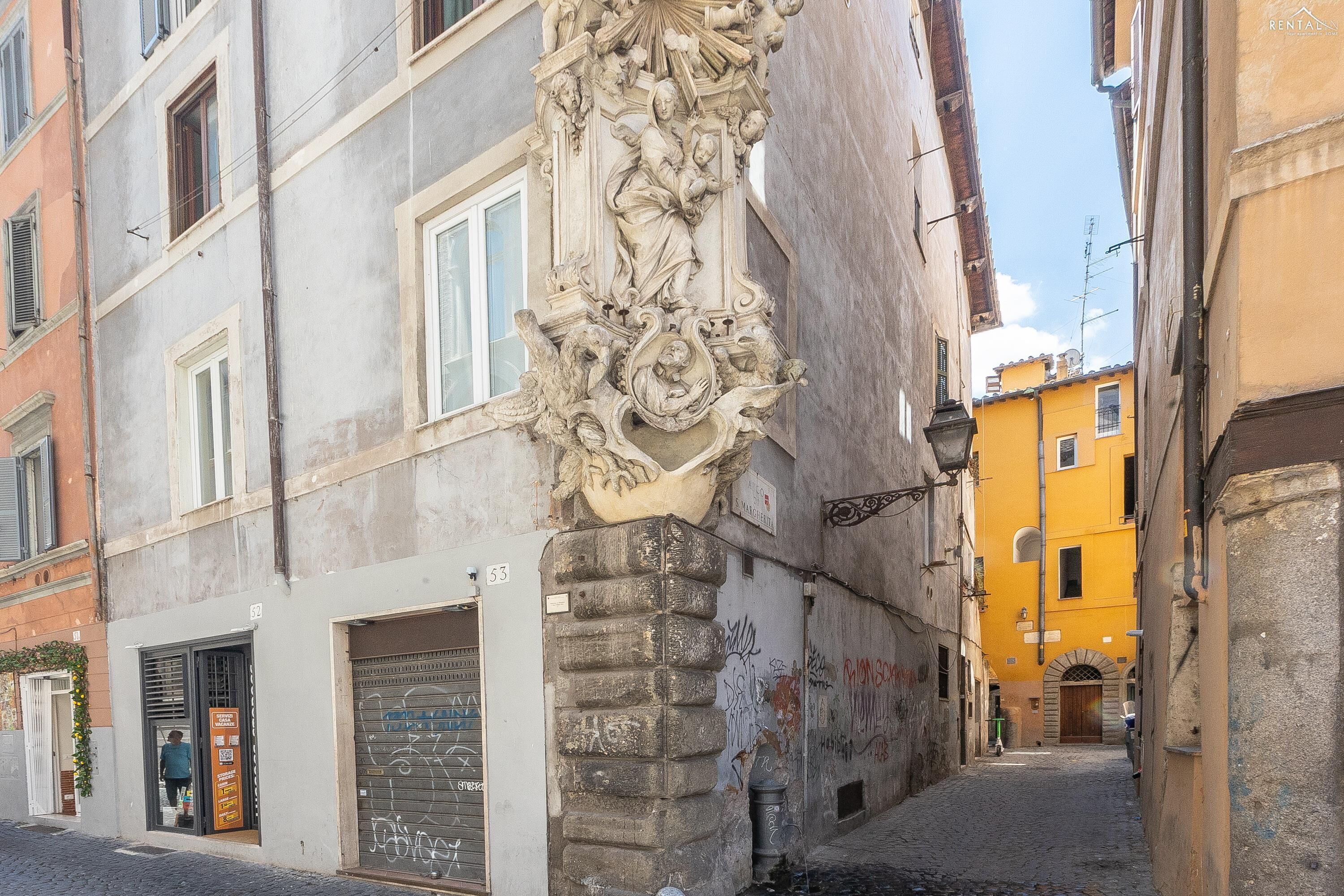 A narrow street with a building featuring a decorative stone column and a door with a sign.