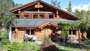 Una cabaña de troncos con un letrero que dice 'Brie-Gite', revestimiento de madera y un patio con mobiliario exterior.