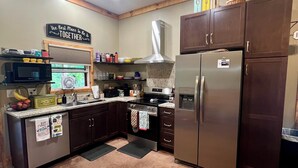 A kitchen with dark wooden cabinets, stainless steel appliances, and a sign on the wall.