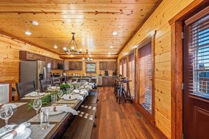 A wooden interior with a dining area, kitchen, and large windows.