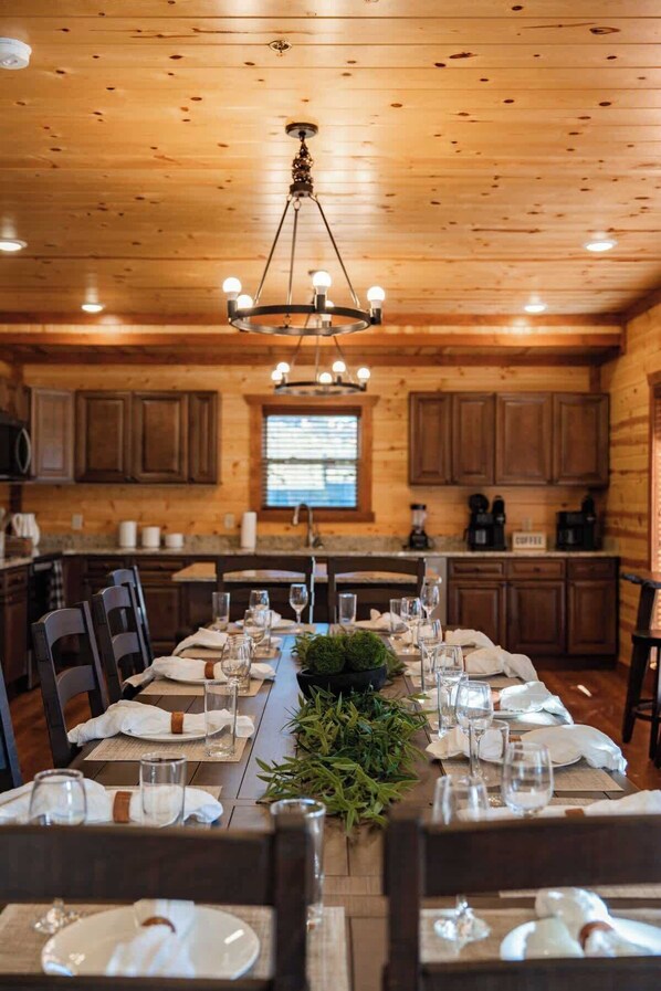 A wooden interior with a dining table set for six, surrounded by wooden cabinets and a chandelier.
