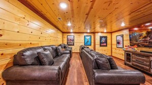 A wooden-paneled room with leather sofas and a television.