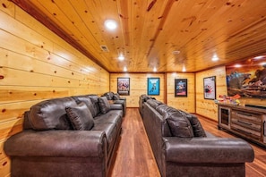 Una habitación con paneles de madera, sofás de cuero y una televisión.