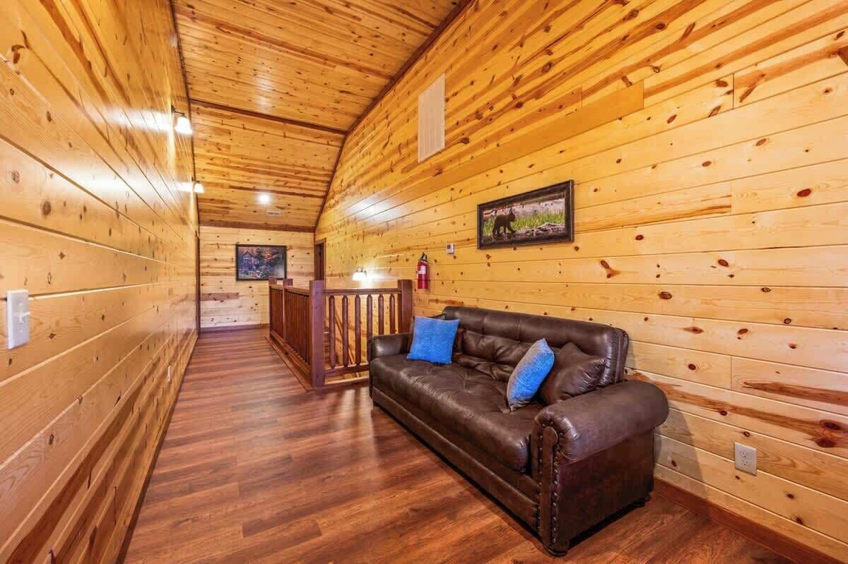 A wooden interior with a leather sofa, wooden walls, and a wooden floor.