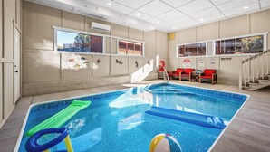 An indoor swimming pool with a view of a building through a window.