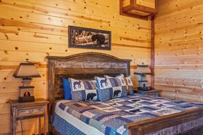 Habitación de cabaña de madera con una cama, dos mesitas de noche y un cuadro enmarcado en la pared.