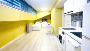 A compact kitchen with a washing machine, a small dining area, and a TV. - ABC Homestay Guesthouse (Incheon)