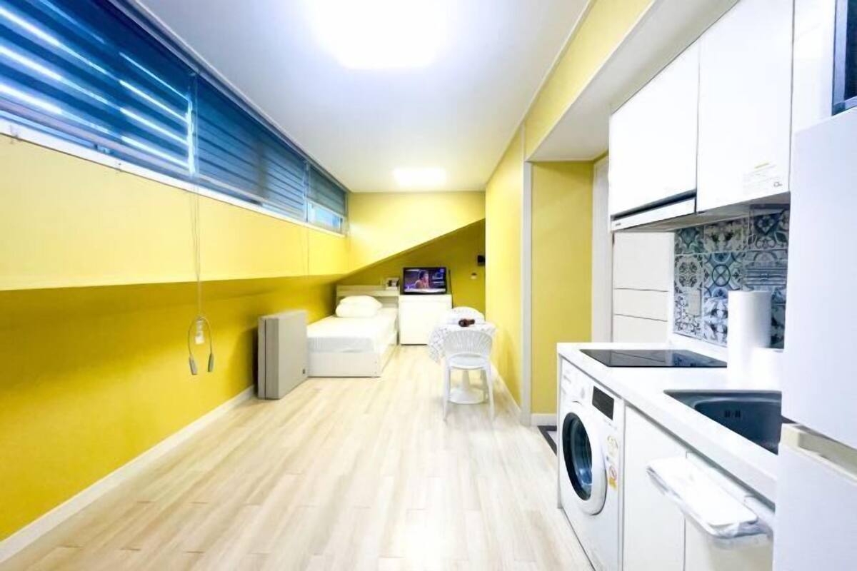 Cocina compacta con lavadora, un comedor pequeño y televisor.