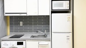 A kitchen with white cabinets, a microwave, a built-in oven, a sink, and a dishwasher. - ABC Homestay Guesthouse (Incheon)