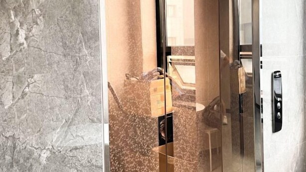 A modern elevator with a glass door, a marble wall, and a small table with a lamp. - ABC Homestay Guesthouse (Incheon)