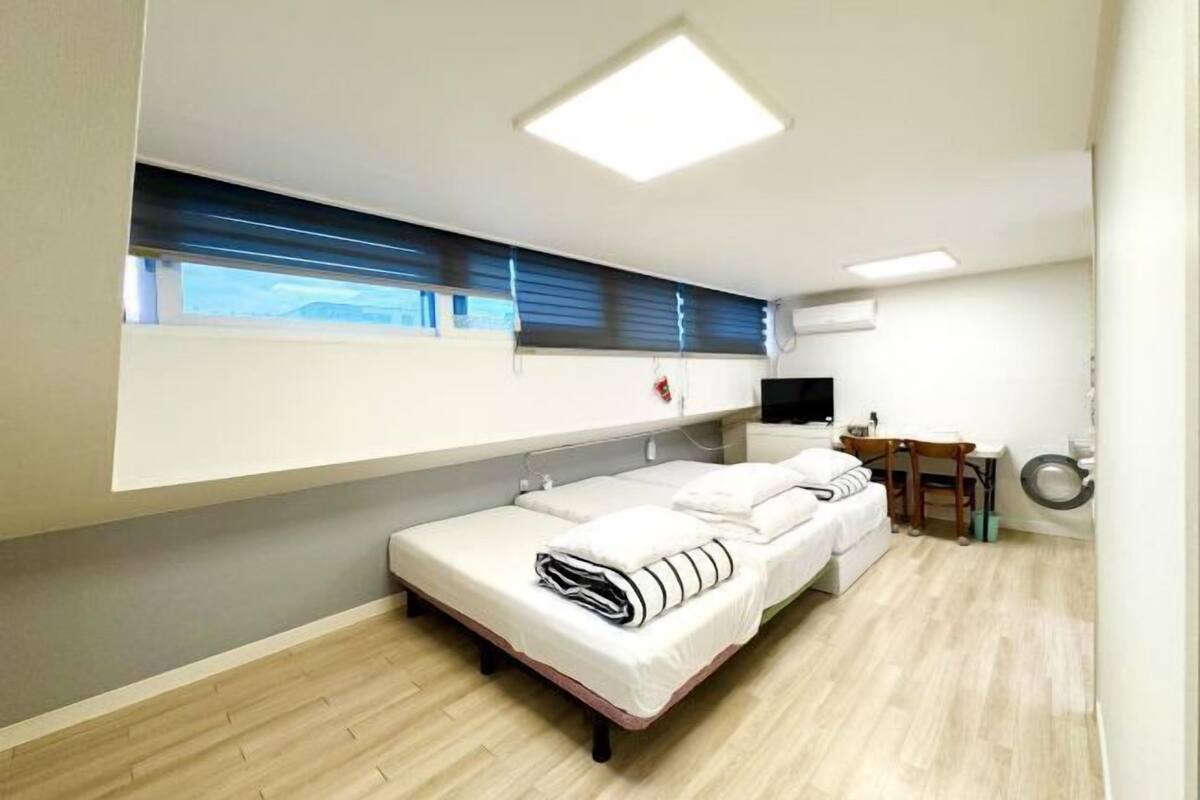 Habitación individual con ventana, escritorio y silla.