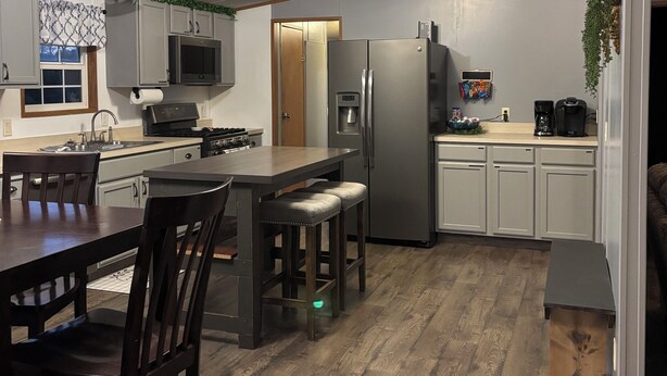 A modern kitchen with a central island, wooden flooring, and a built-in refrigerator. - Beautiful home with pool in Wayne City (Wayne City)