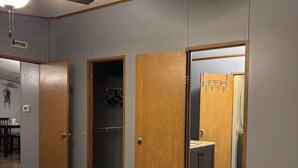 A bedroom with a bed, a ceiling fan, and wooden doors leading to other rooms. - Beautiful home with pool in Wayne City (Wayne City)