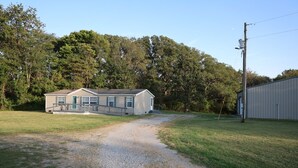 A single-story house with a gravel driveway leading to a front porch. - Beautiful home with pool in Wayne City (Wayne City)