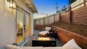 An outdoor patio with a fire pit, seating area, and a wooden fence.