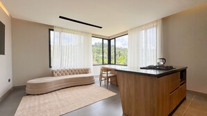 Una cocina moderna con una isla integrada, un sofá y ventanas amplias que ofrecen vistas al exterior.
