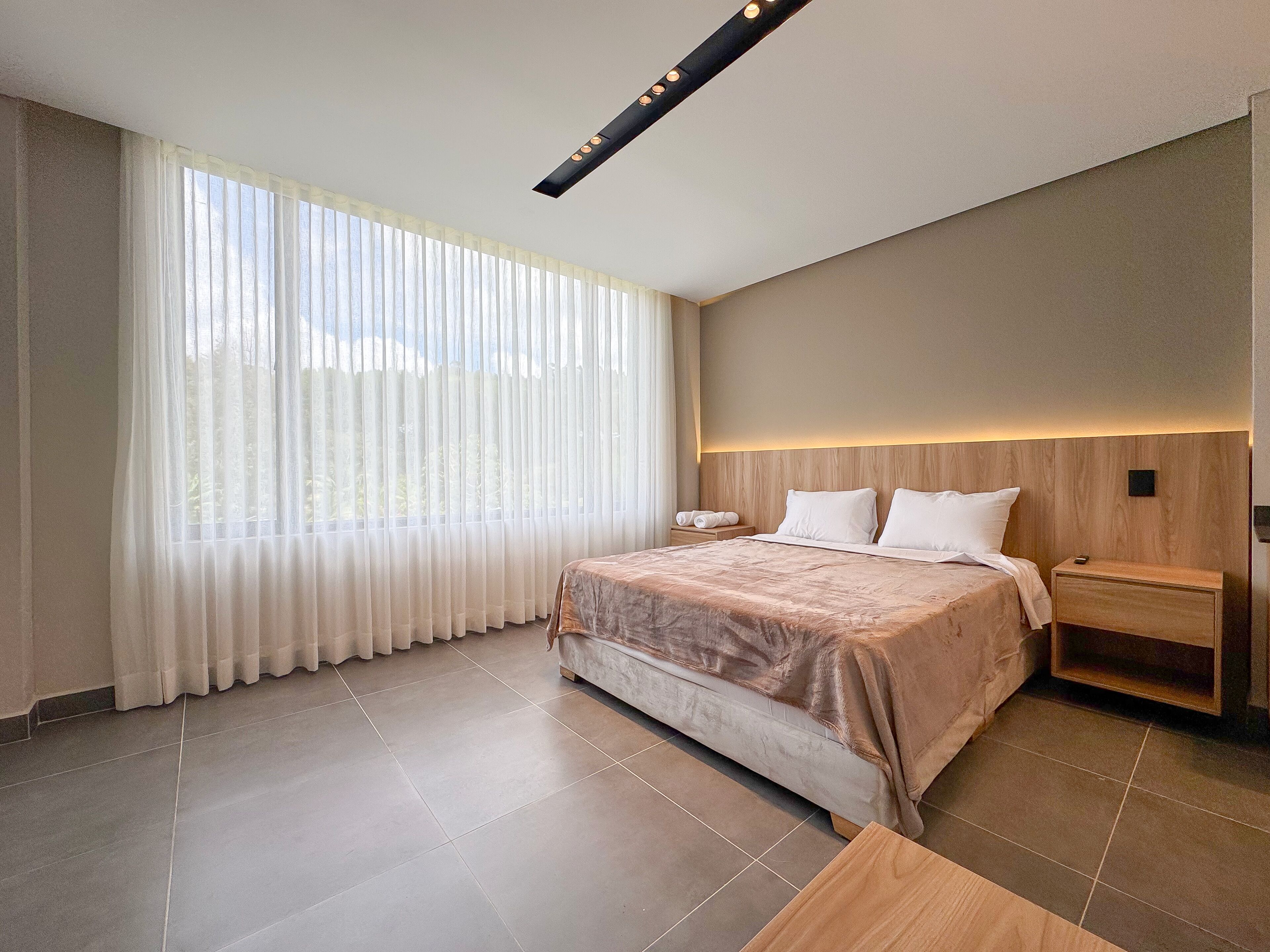 A modern hotel room with a large bed, a bedside table, and a nightstand.