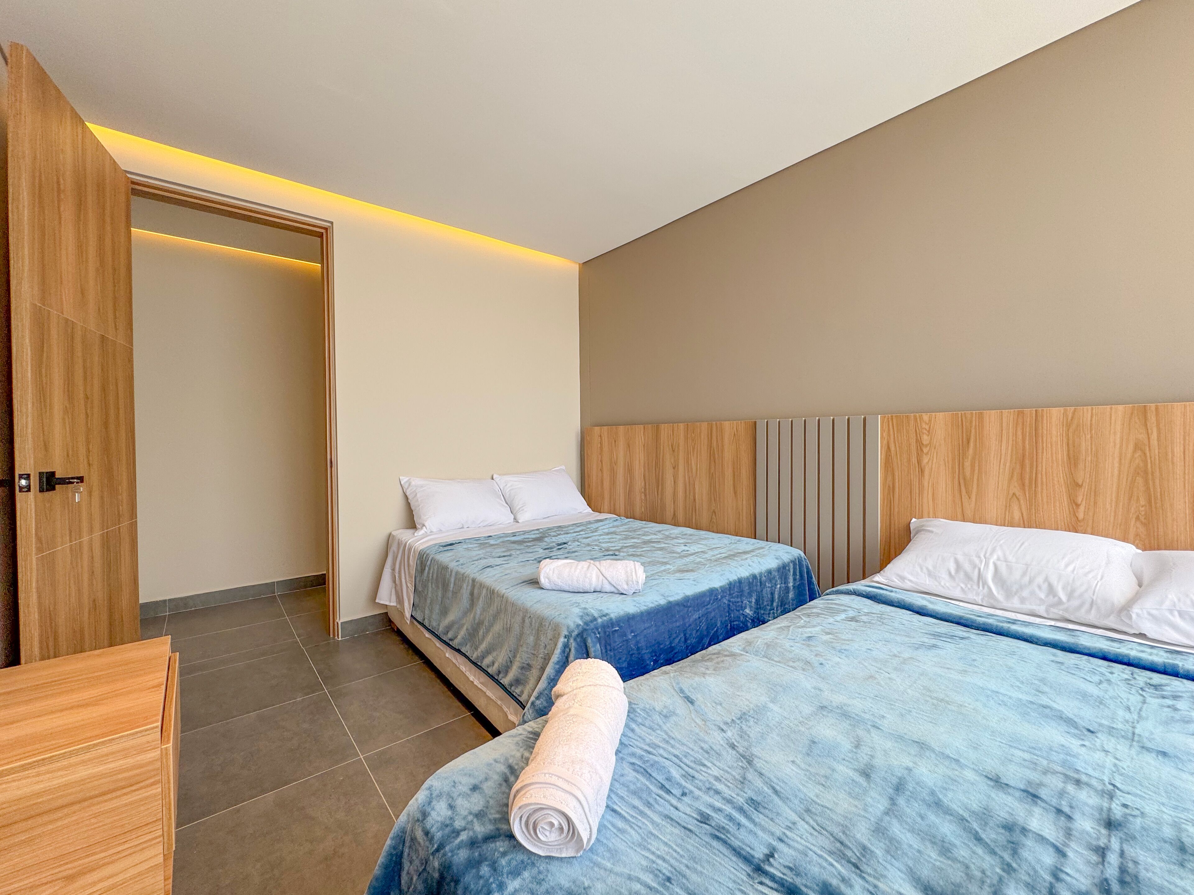 Une chambre d’hôtel avec deux lits, des têtes de lit en bois et une armoire en bois.