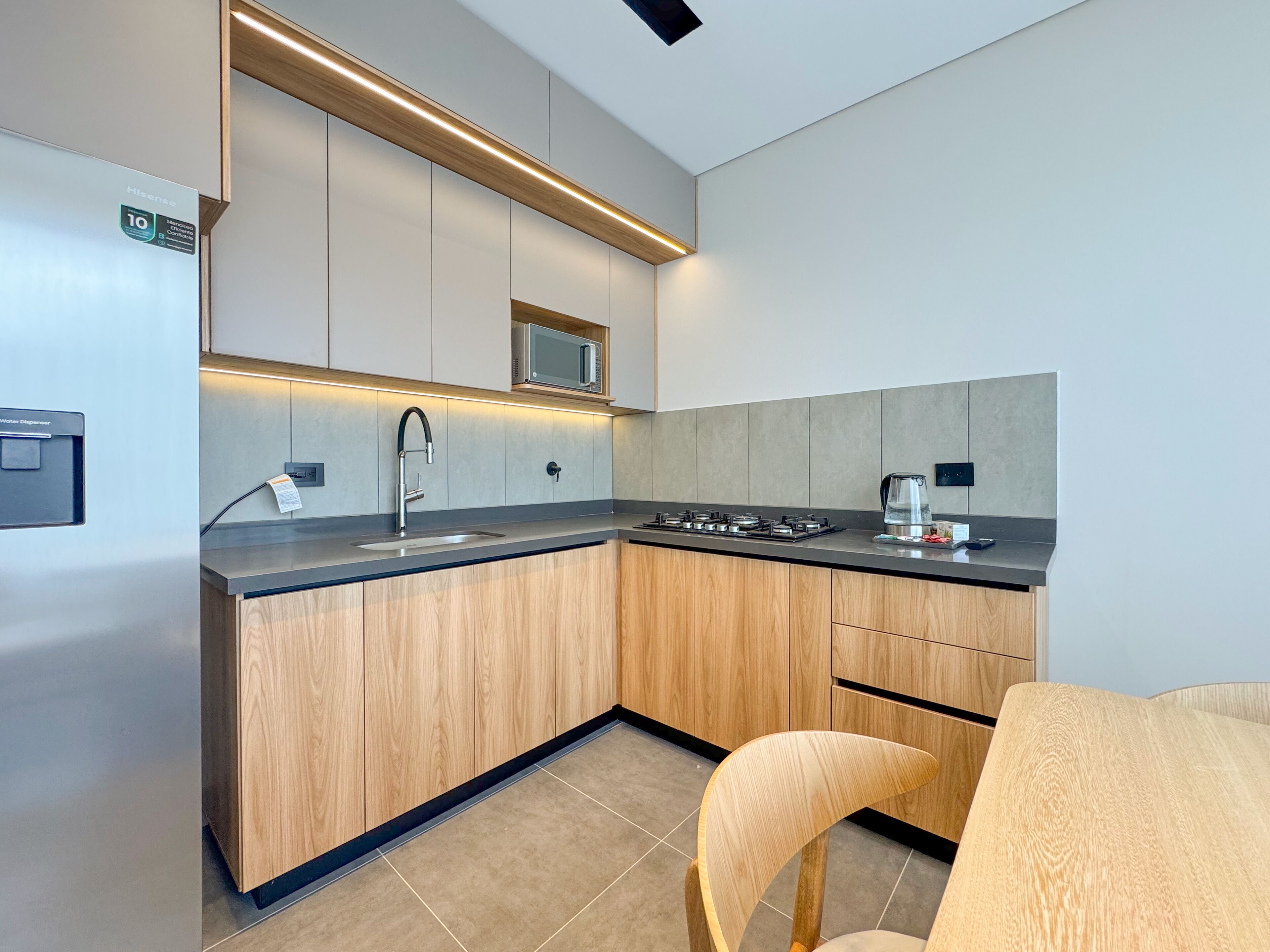 Een moderne keuken met een ingebouwde magnetron, een waterdispenser en een gasfornuis.