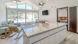 A modern kitchen with a large island, a dining area with a table and chairs, and a seating area with a sofa and chairs. - Surfer`s Oasis Pool Villa The Point Playa Avellana (Playa Avellanas)