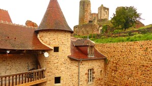 A stone building with a turret, a balcony, and a view of a castle in the background. - Holiday Home 'L'ancien Collège' with Private Pool, Wi-Fi and Air Conditioning (Hérisson)