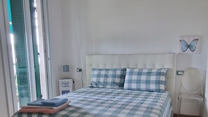 Un dormitorio con cama, ventilador de techo, mesita de noche y ventana.