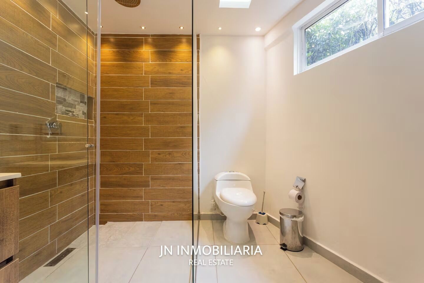 A modern bathroom with a glass shower enclosure, a toilet, and a bidet.