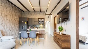 A modern living room with a sofa, dining table, chairs, a TV, and a kitchen area with a microwave and refrigerator. - Cabañas Cielo Verde (Rionegro)