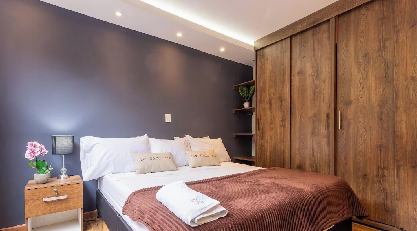 Une chambre à coucher comprenant un lit, une table de chevet, une commode et une armoire.